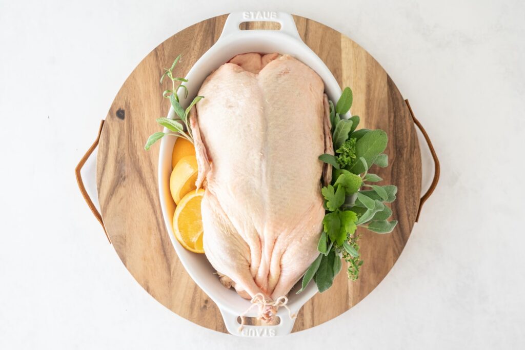 Whole raw duck in a pan herbs and citrus